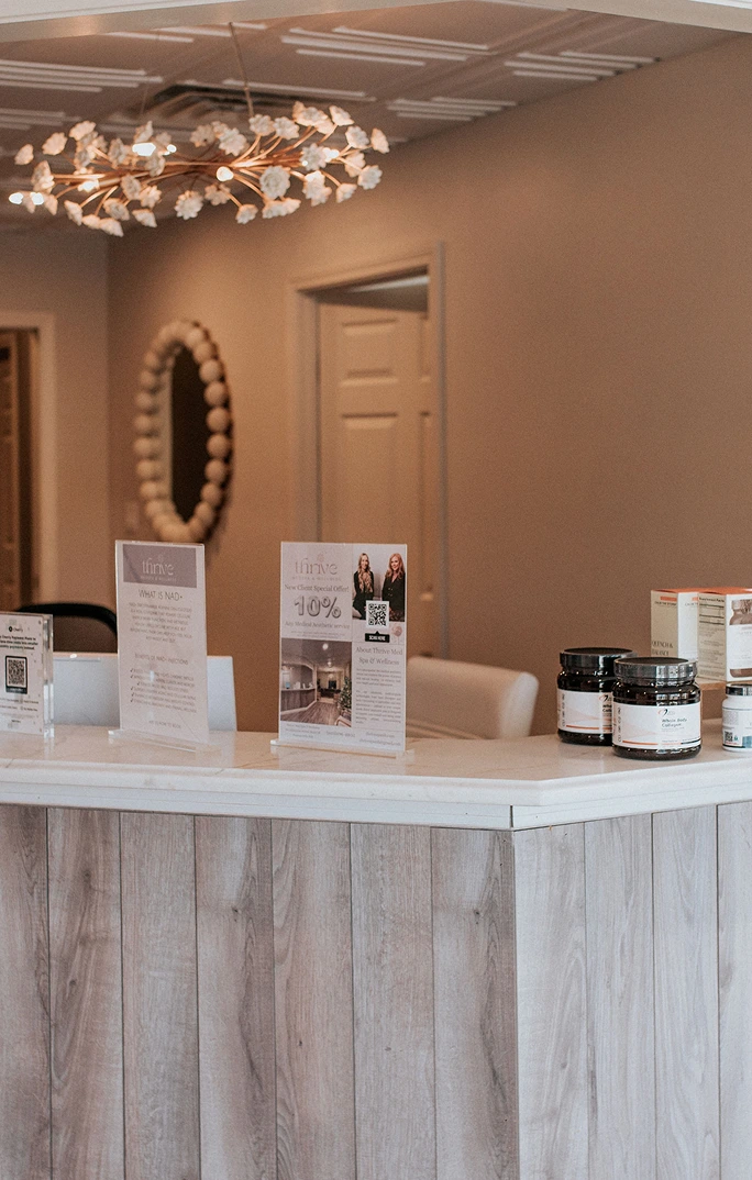 Thrive Med Spa reception desk with promotional materials, product jars, and decorative lighting fixture