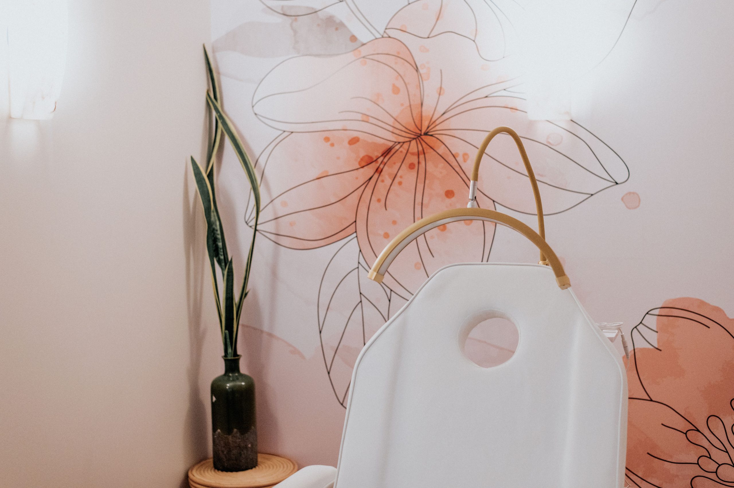 Spa setting with white waxing pot, botanical decor, and floral wall art in warm tones