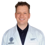 Michael Henderson, APNP, PMHNP, wearing a white coat with Mental Health Relief logo, smiling at camera
