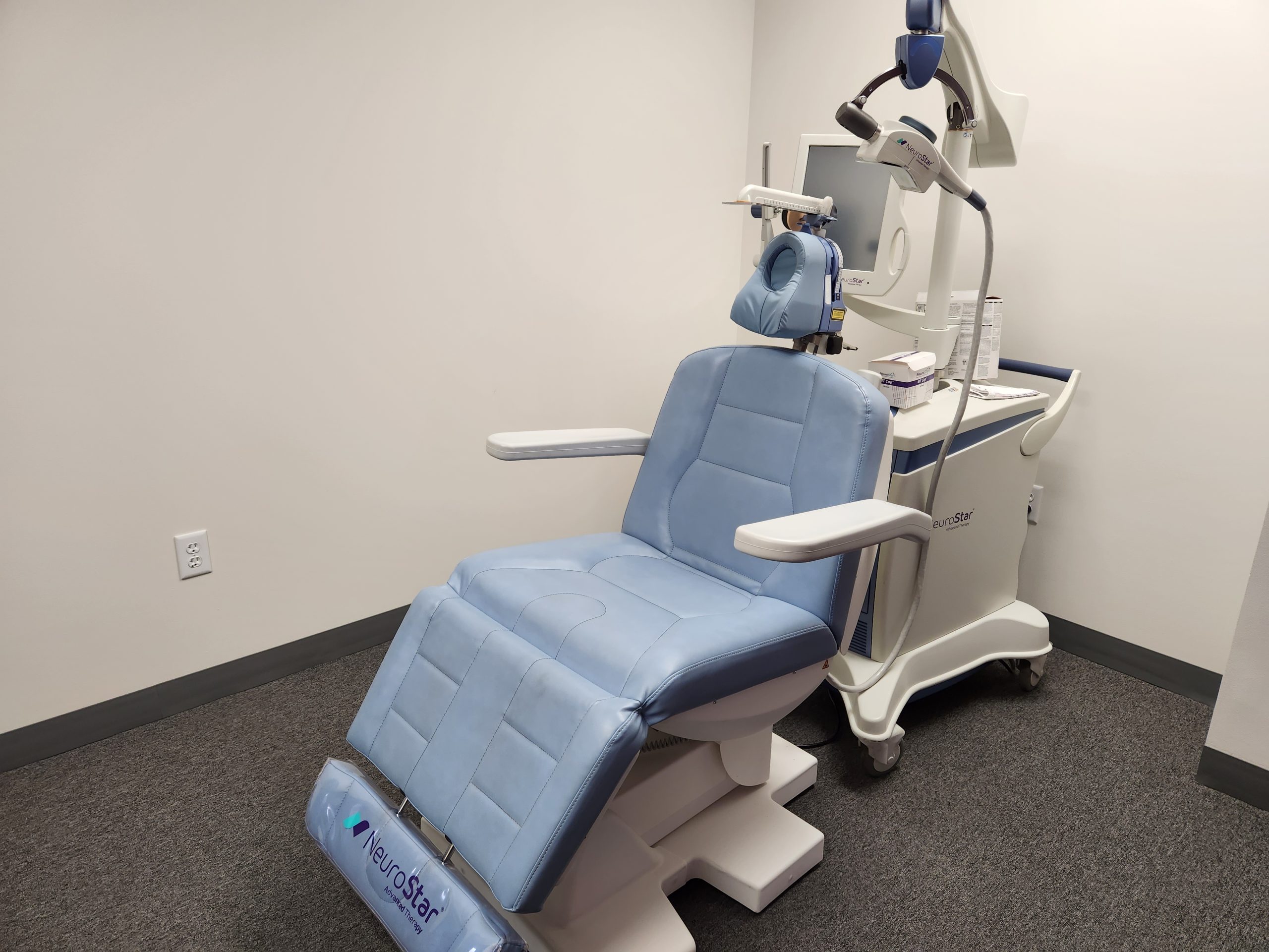 TMS therapy treatment chair with headgear and coil apparatus in clinical room