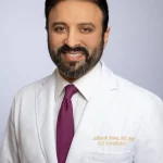 Siddharth Arora, DO, MS, pain management specialist, in white coat and purple tie
