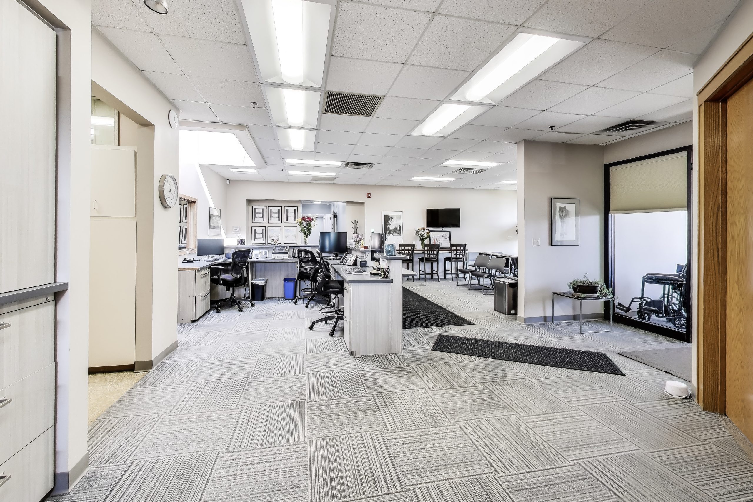 Open-plan office with workstations, desks, and seating area in a medical practice setting