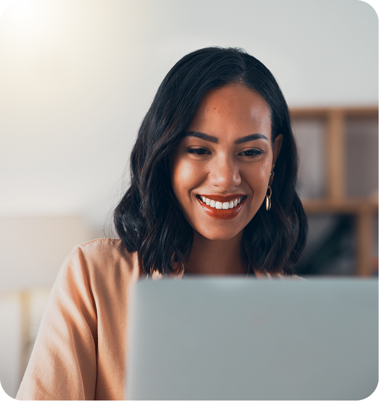 Woman smiling while looking at laptop screen in bright office setting