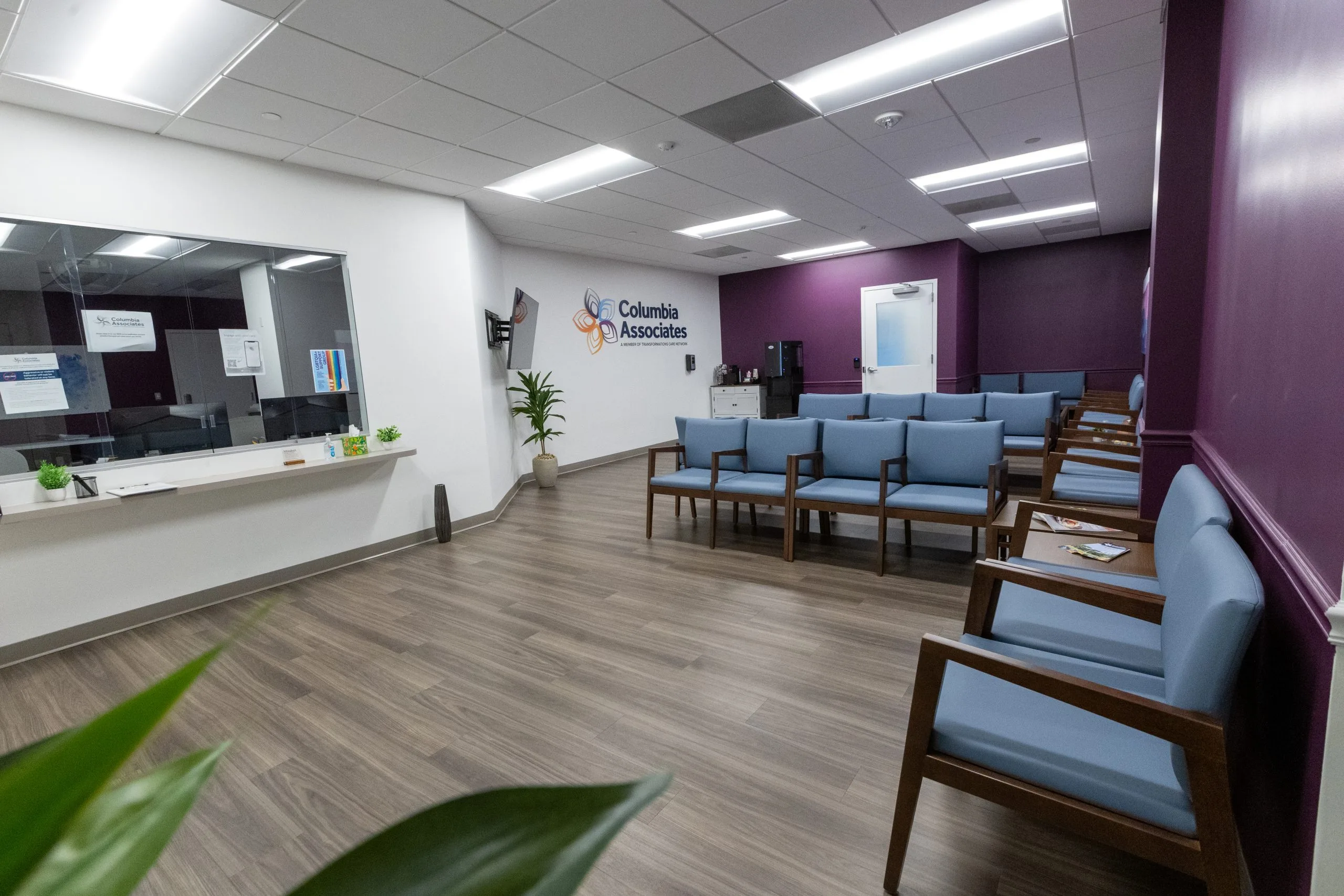 Columbia Associates medical office waiting room with reception desk, blue upholstered chairs, and purple accent wall