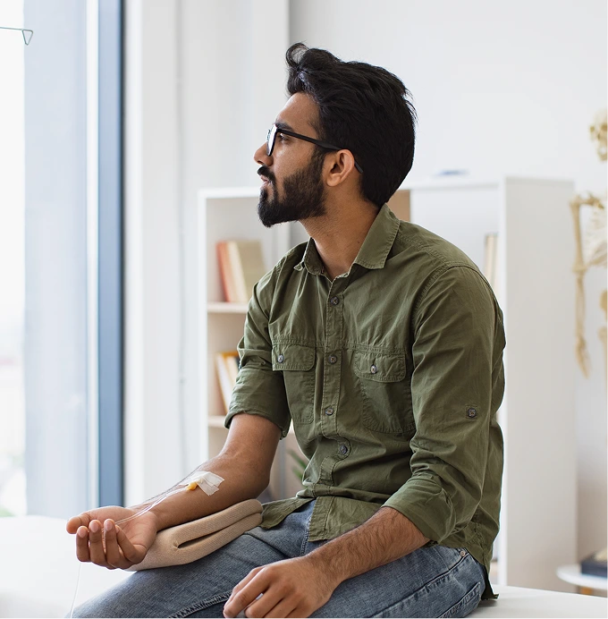 Man sitting in a clinic room with a bandage on his arm after ketamine infusion therapy