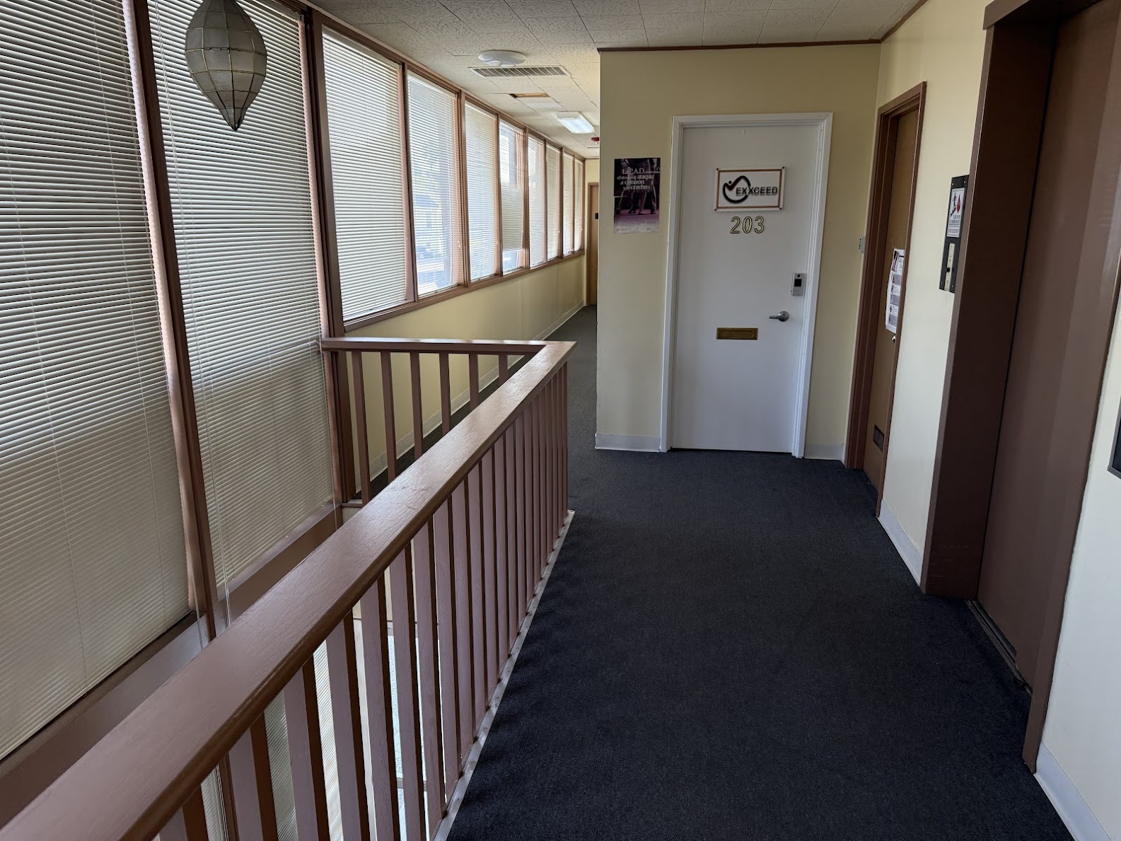 Hallway with frosted glass partitions, office door numbered 203, and dark carpeting in a medical office building