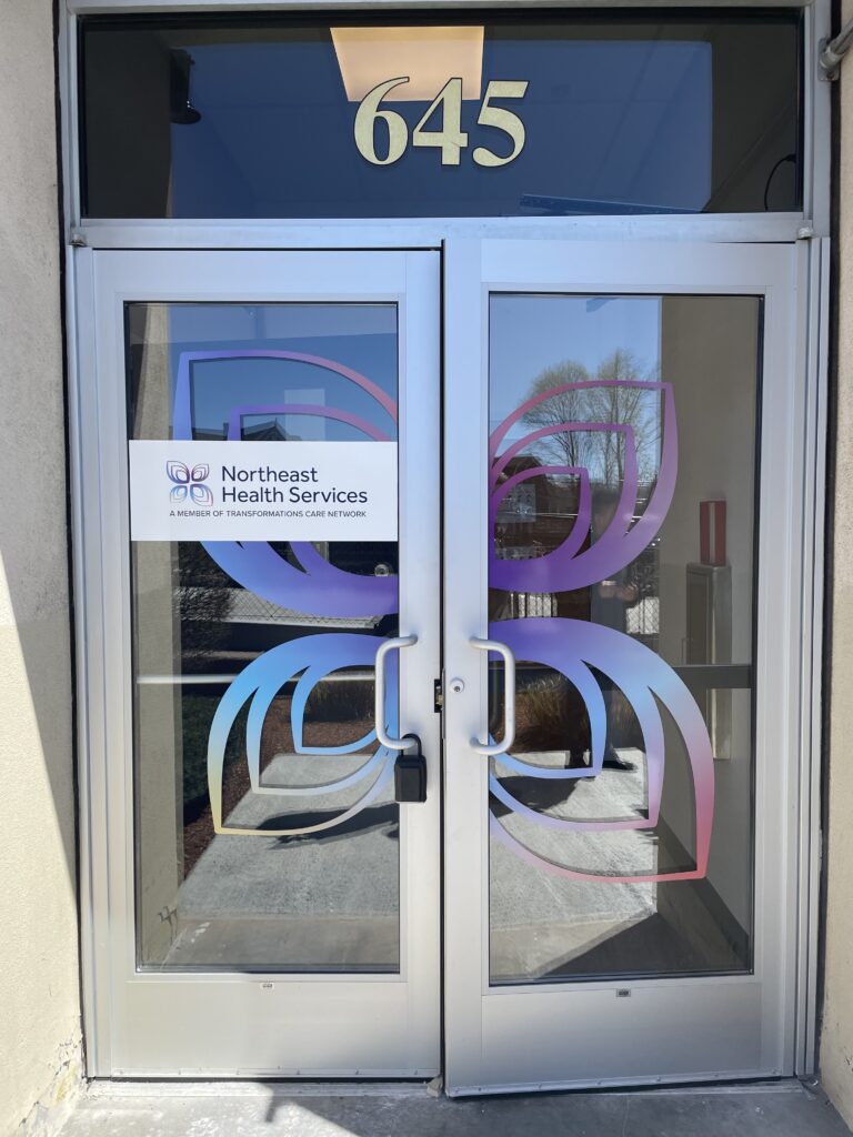 Northeast Health Services entrance at 645 Somersville with blue and purple logo on glass doors
