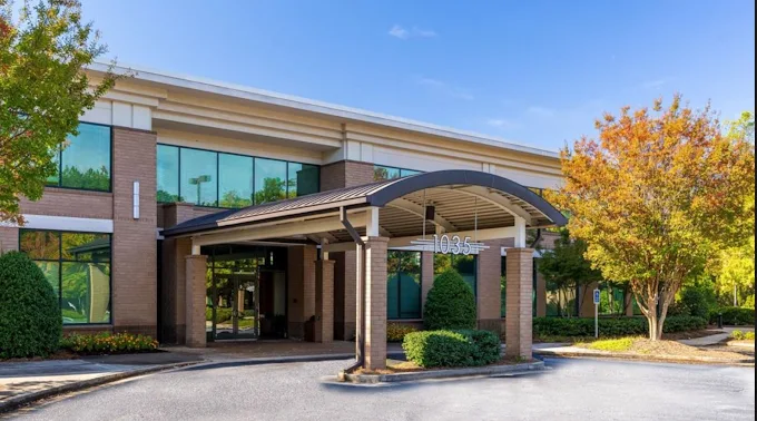 Modern medical office building with brick and glass exterior, curved awning entrance, and manicured landscaping