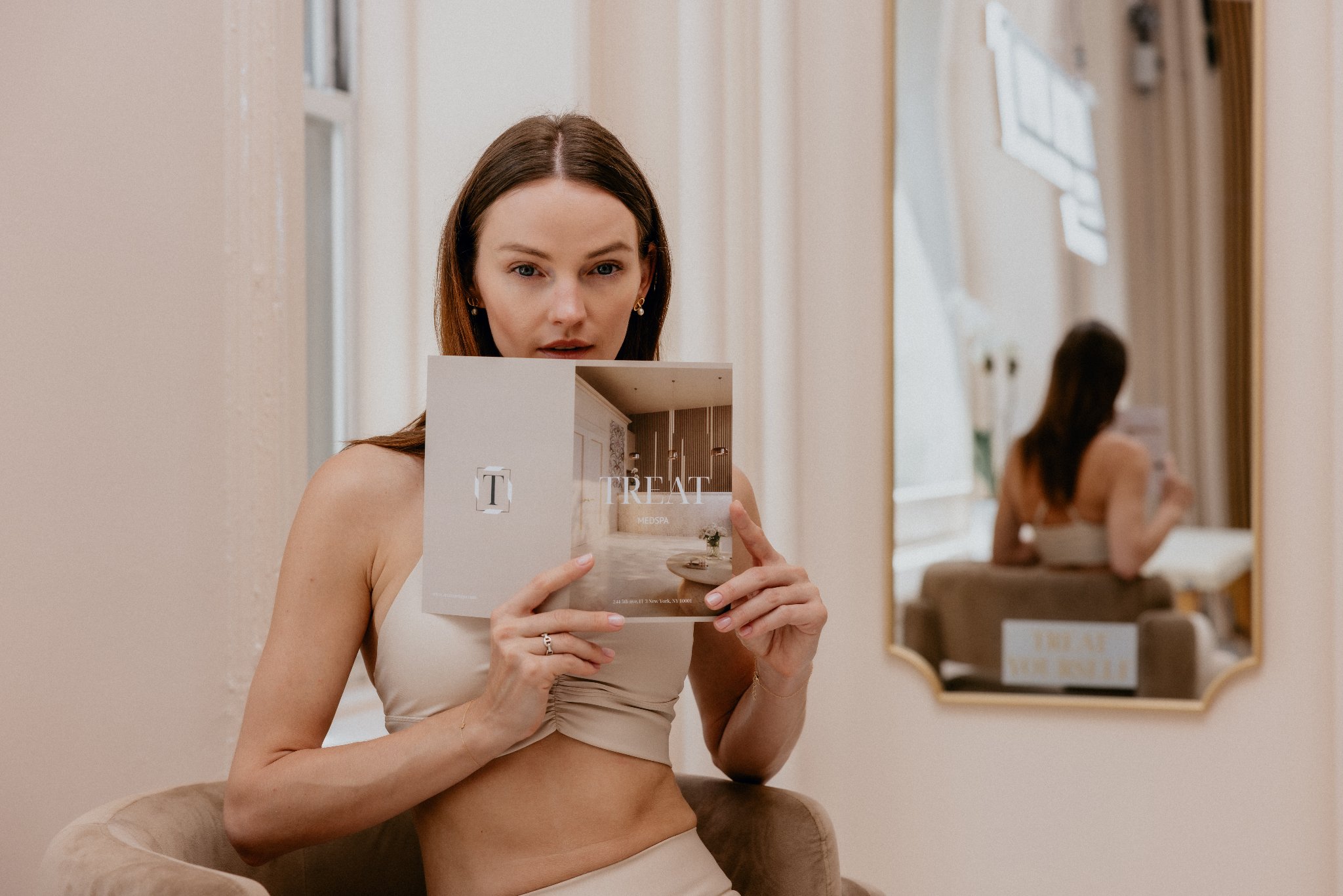 Woman holding Treat Medspa branding material in a spa setting
