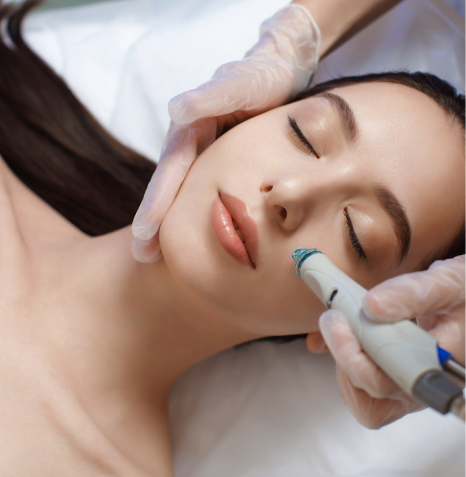 Practitioner using HydraFacial device on patient's cheek during facial treatment