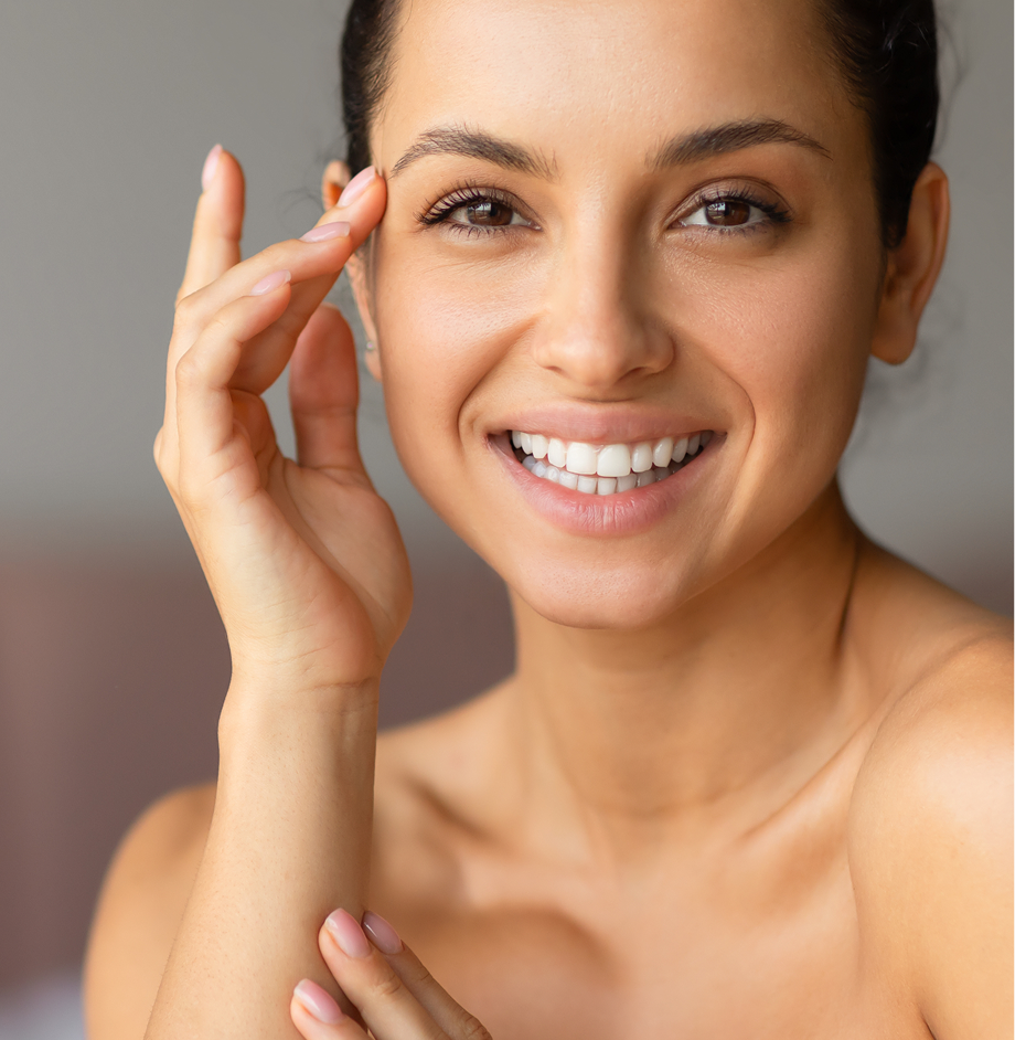 Woman smiling while gently touching the skin under her eye