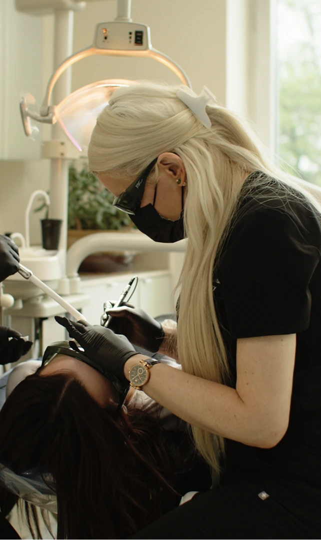 Dentist performing porcelain veneer treatment on patient under overhead light in Manhattan dental office
