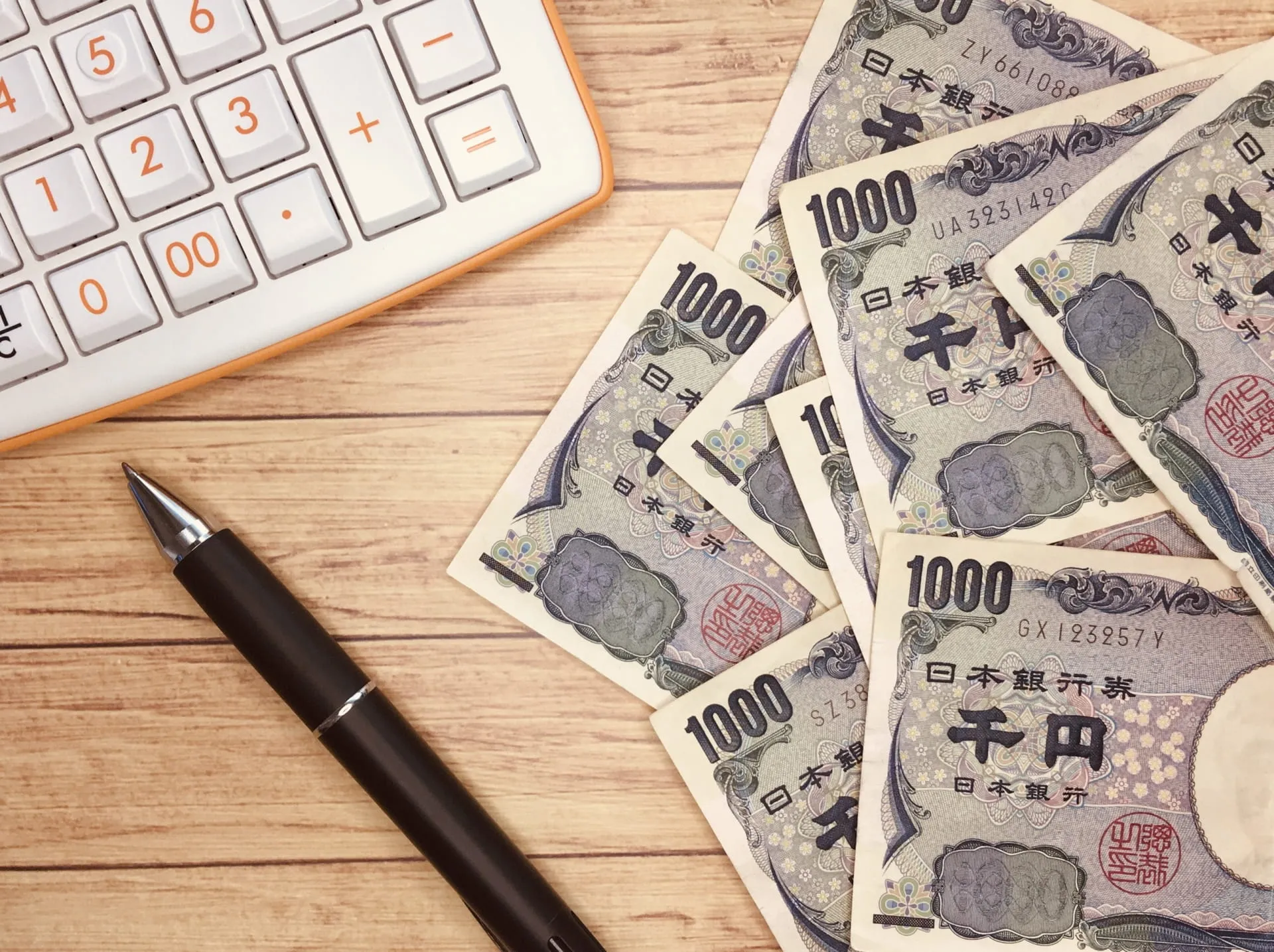 散らばったお金と電卓とペン