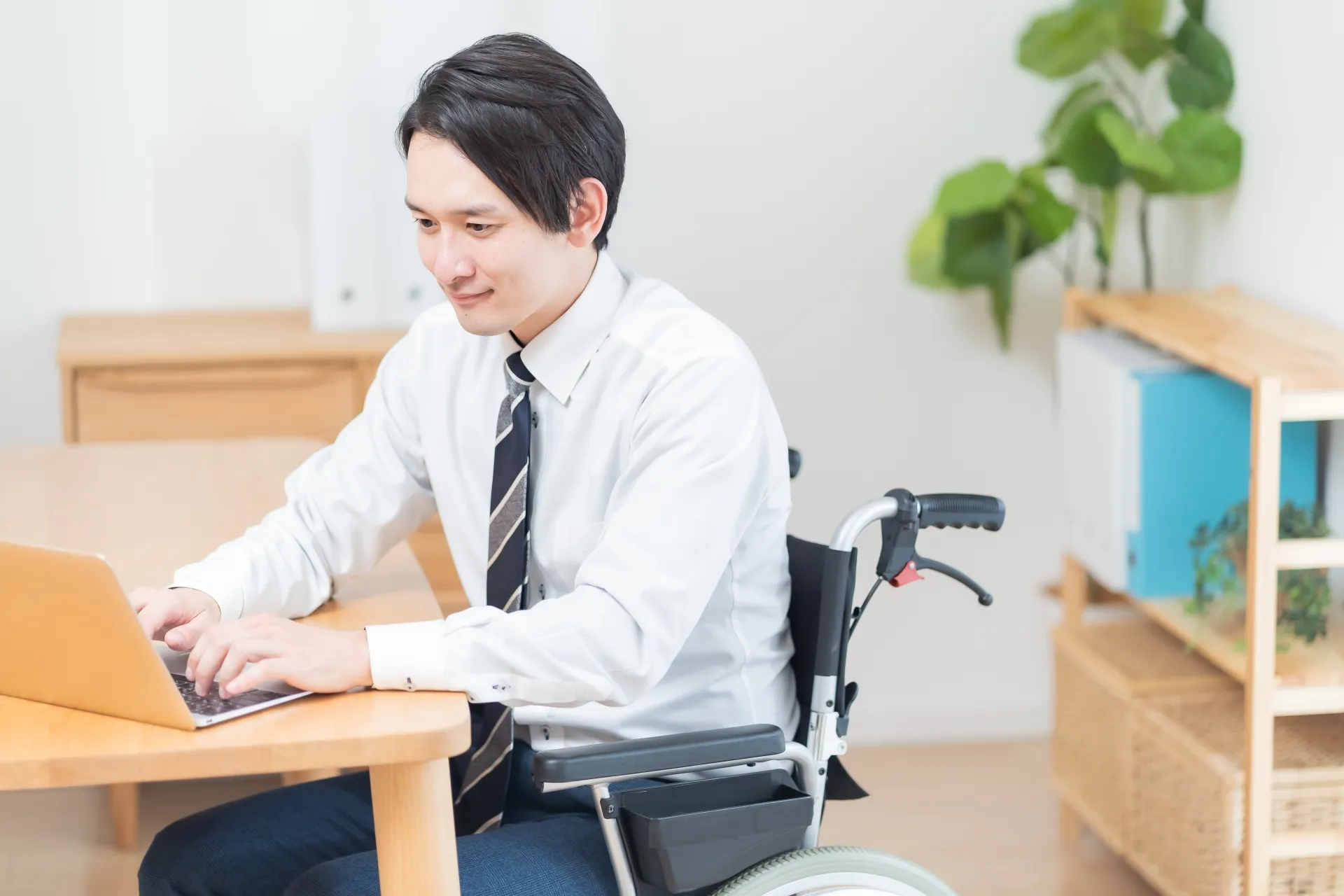 A man in a suit sitting in a wheelchair working on a computer