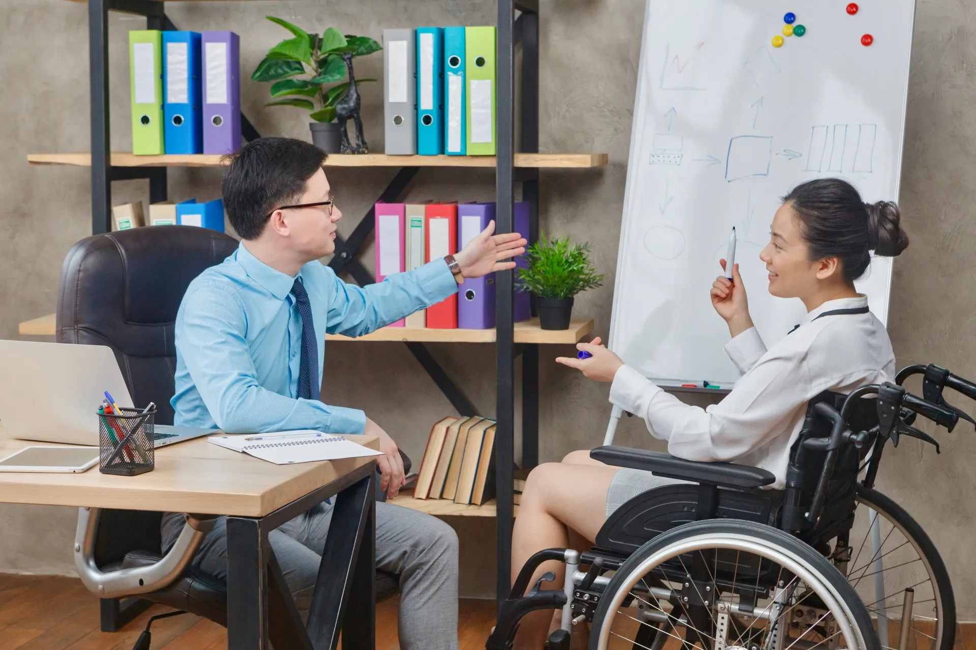 A man and woman having a meeting. The woman is a wheelchair user.