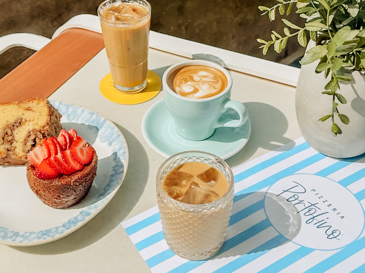 an iced coffee, latte, and pastry on a table with a striped menu under it