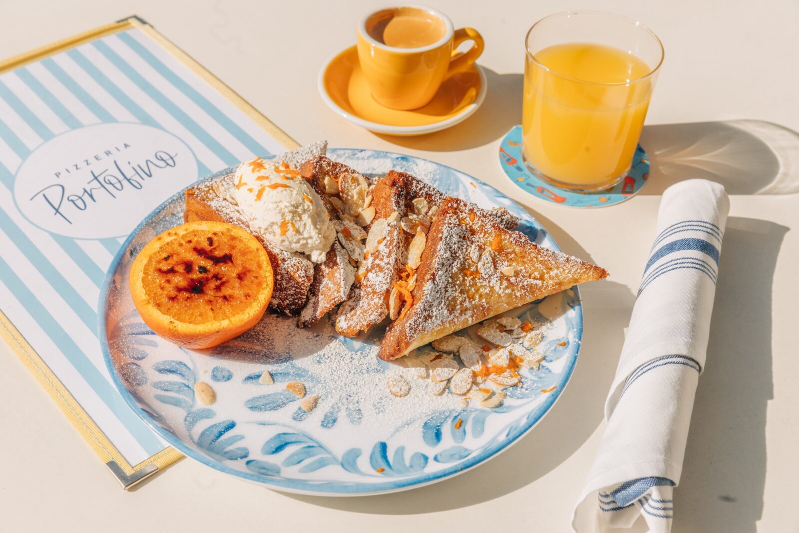 Pieces of french toast with butter on top and orange juice next to it