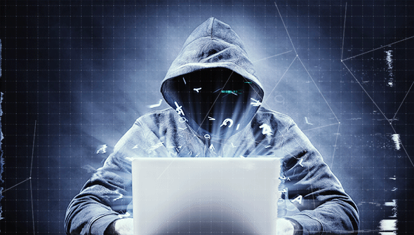 A hooded figure hacks into a computer.