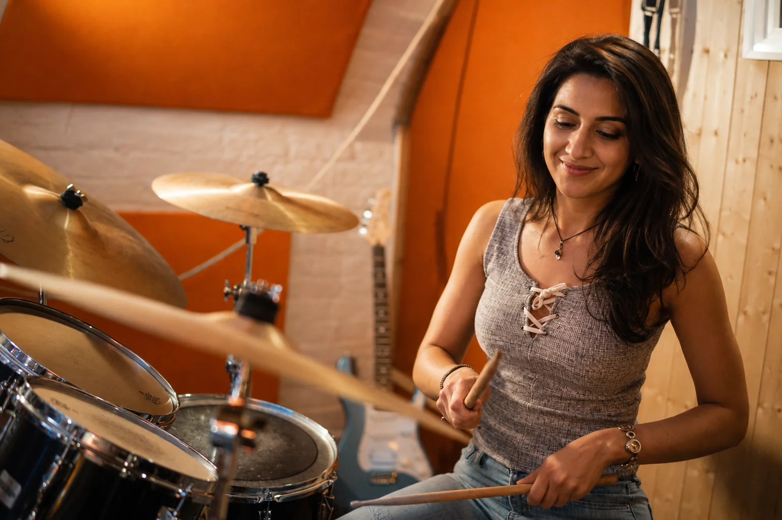 A smiling adult student playing drums at Planet drum