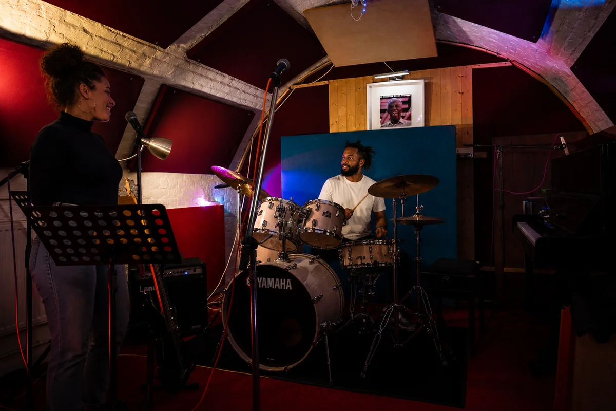 A singer and drummer rehearsing together in the studio