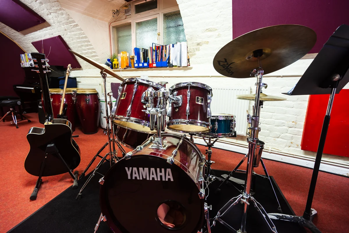 A fully equipped drum practice room at Planet drum, with kit, congas and guitar