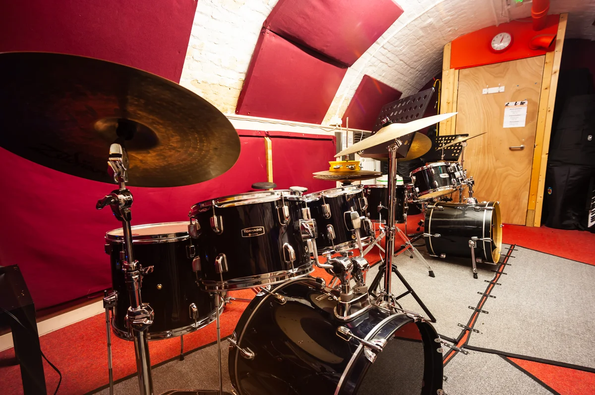 Photo of a drum practice room at Planet drum with full acoustic kit, cymbals and music stand
