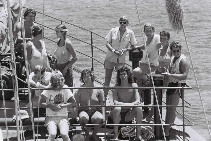 A black and white group shot of crew members relaxing on a boat