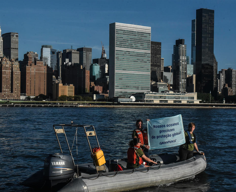 Ativistas seguram banner com a frase "Nossos oceanos precisam de proteção global". 