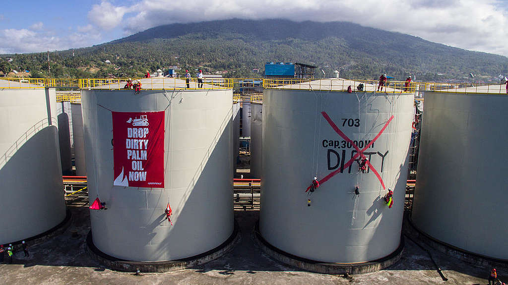 Ativistas abrem um imenso banner em cima de grandes tanques da refinaria da Wilmar. © Rendra Hernawan