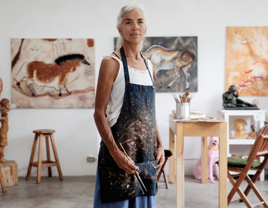 Painter proudly standing in front of her work in the studio.
