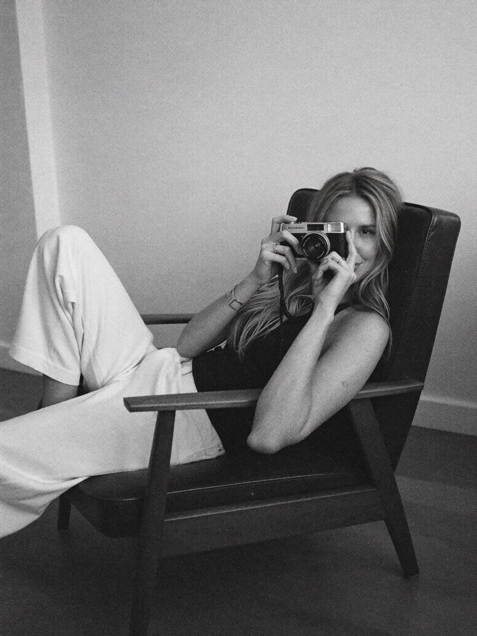 Black-and-white portrait of Madeline seated with a camera