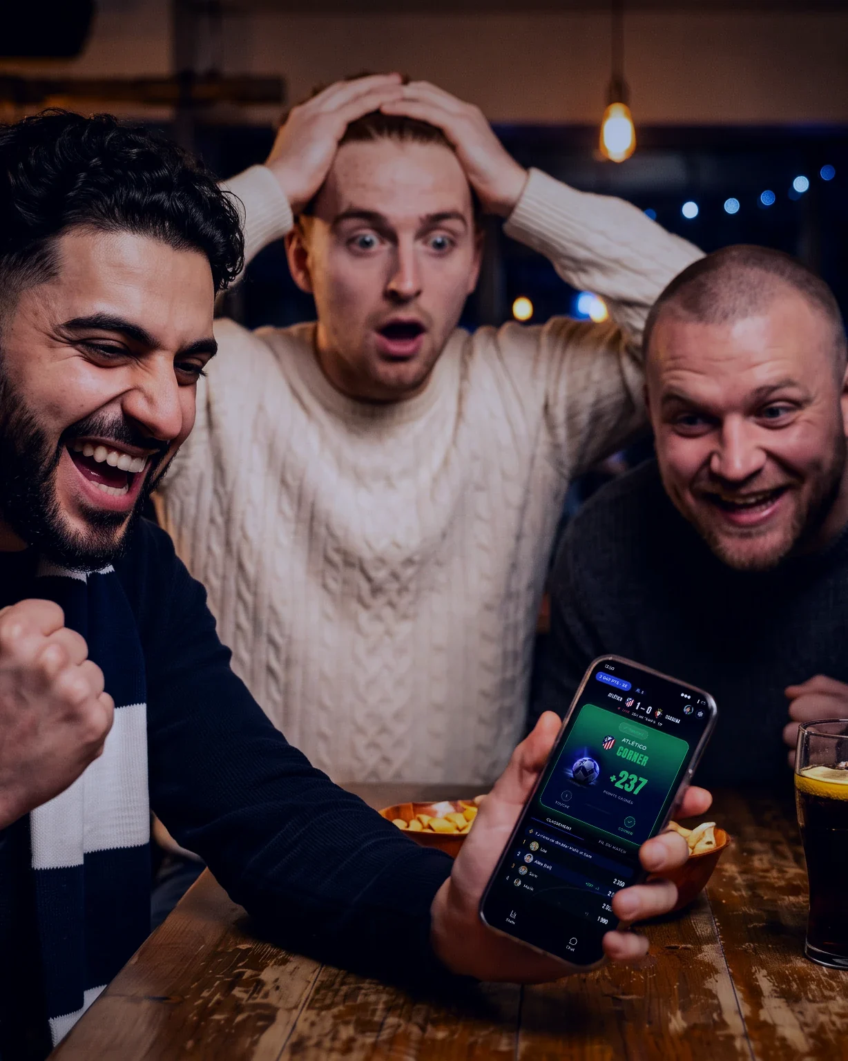 Dans un bar pendant un match, quatre potes réagissent autour d'un téléphone affichant l'écran live Winble avec un corner à +237 points : l'un serre le poing, un autre a les mains sur la tête