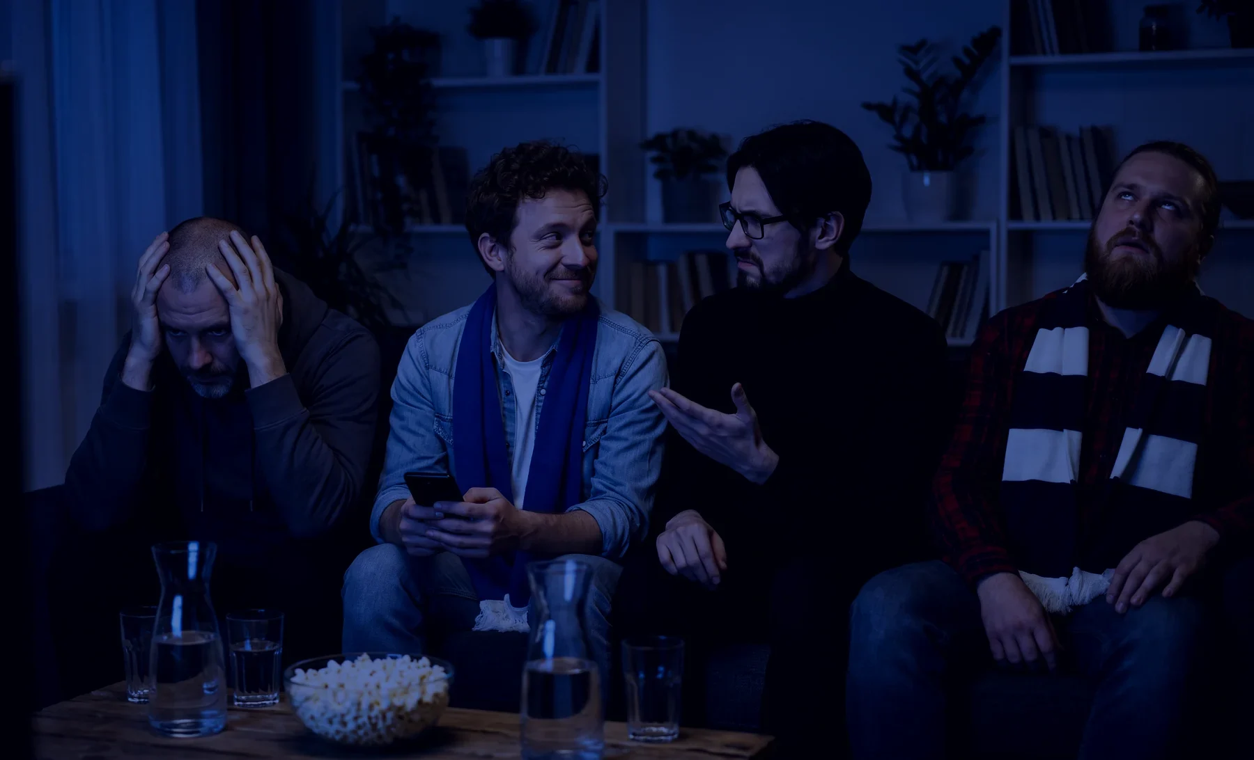 Le soir dans un salon, quatre potes en écharpe sur un canapé : l'un se tient la tête, un autre lève les yeux au ciel, un troisième interpelle son voisin qui, téléphone en main, cache mal un sourire coupable