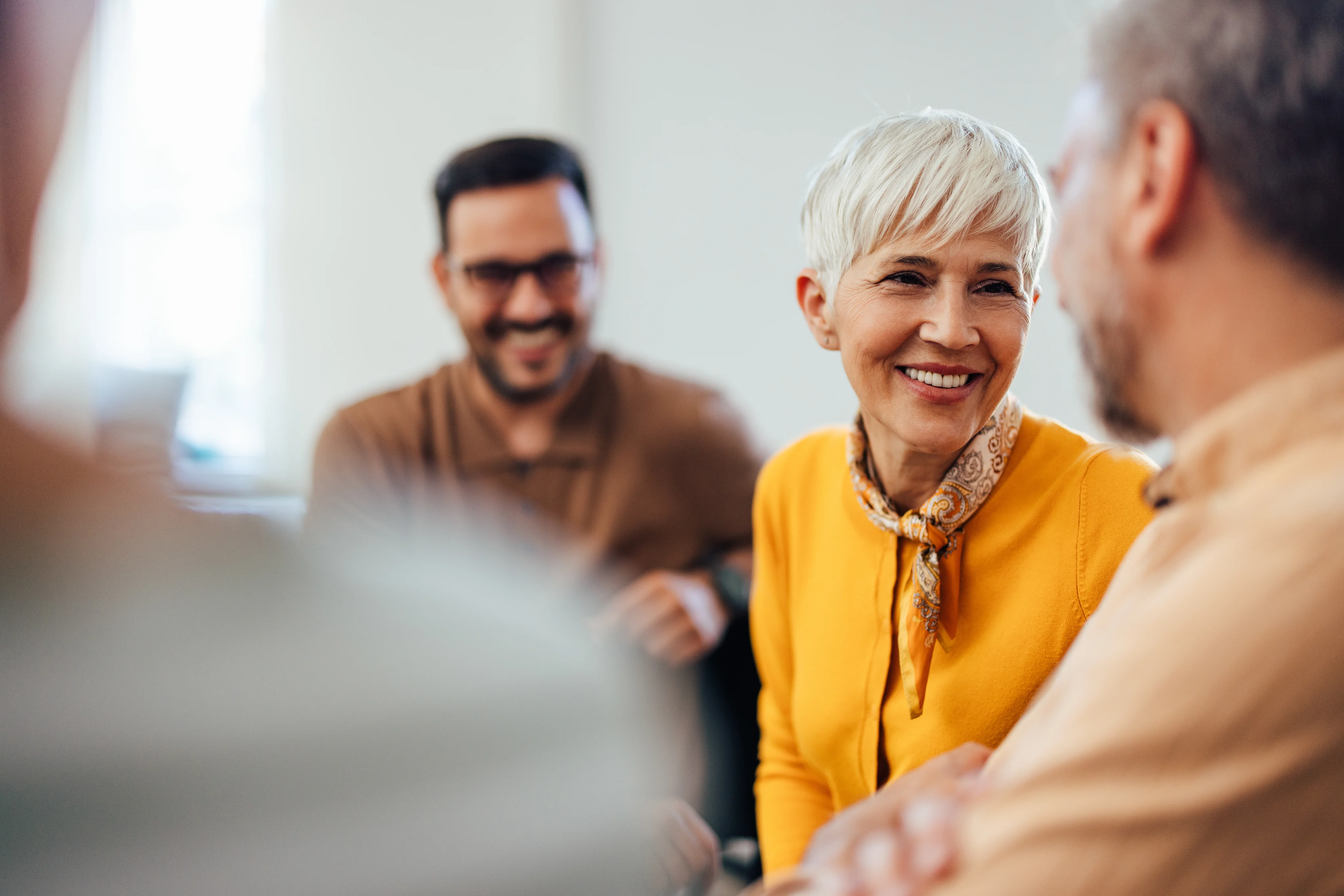 A smiling senior woman with short gray hair talking with others