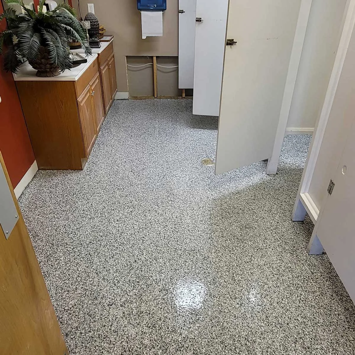 Flake epoxy floor in a restroom with cabinets and stall partitions