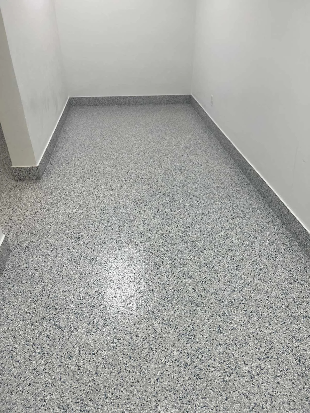 Gray flake epoxy floor in an empty room with a cove base