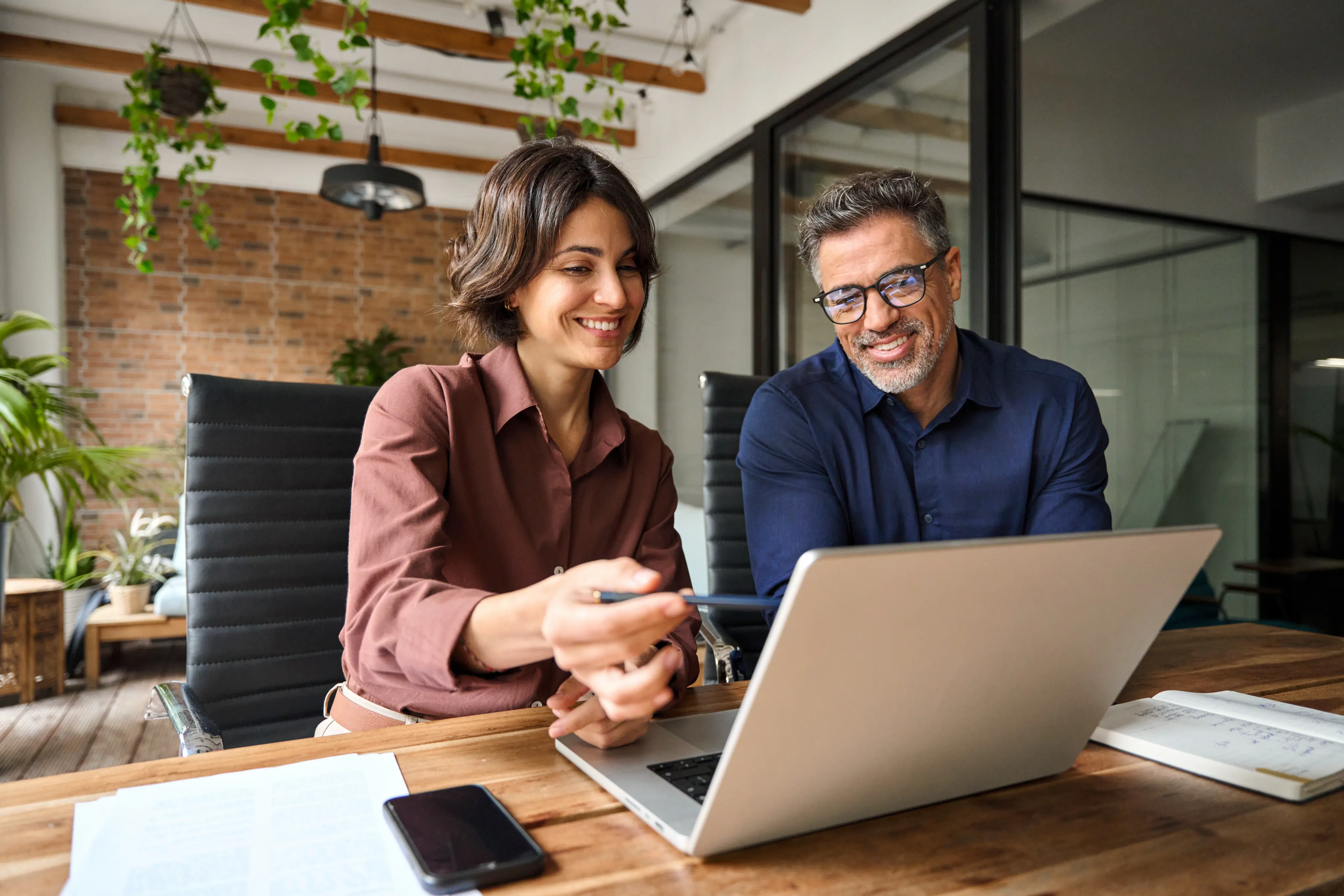 Two colleagues discussing work together on a laptop
