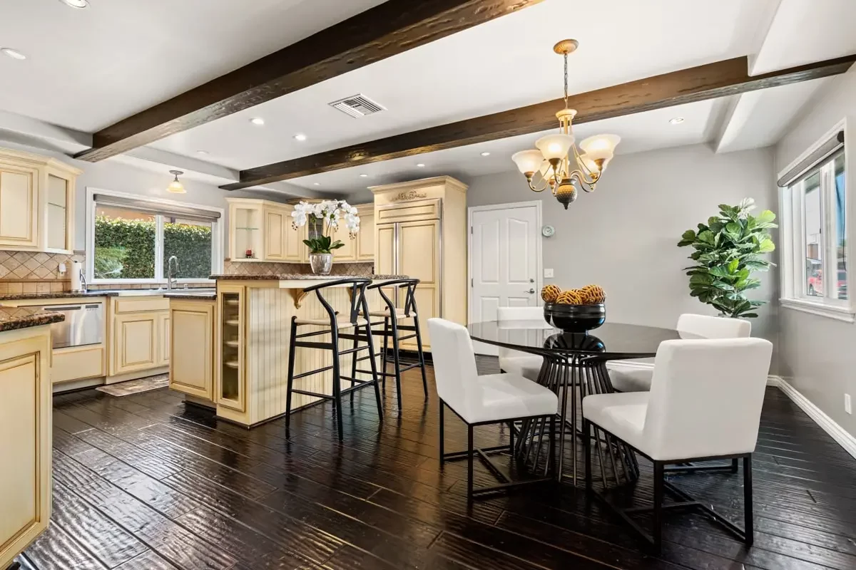 Renaissance Recovery California kitchen and dining area with a beamed ceiling, cream cabinetry, and a glass dining table