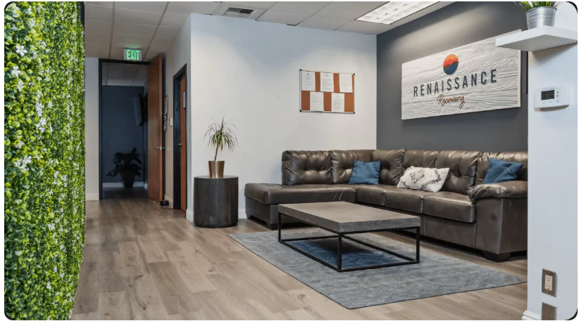 Renaissance Recovery reception lounge with a leather sectional, living-plant wall, and branded RENAISSANCE wall sign