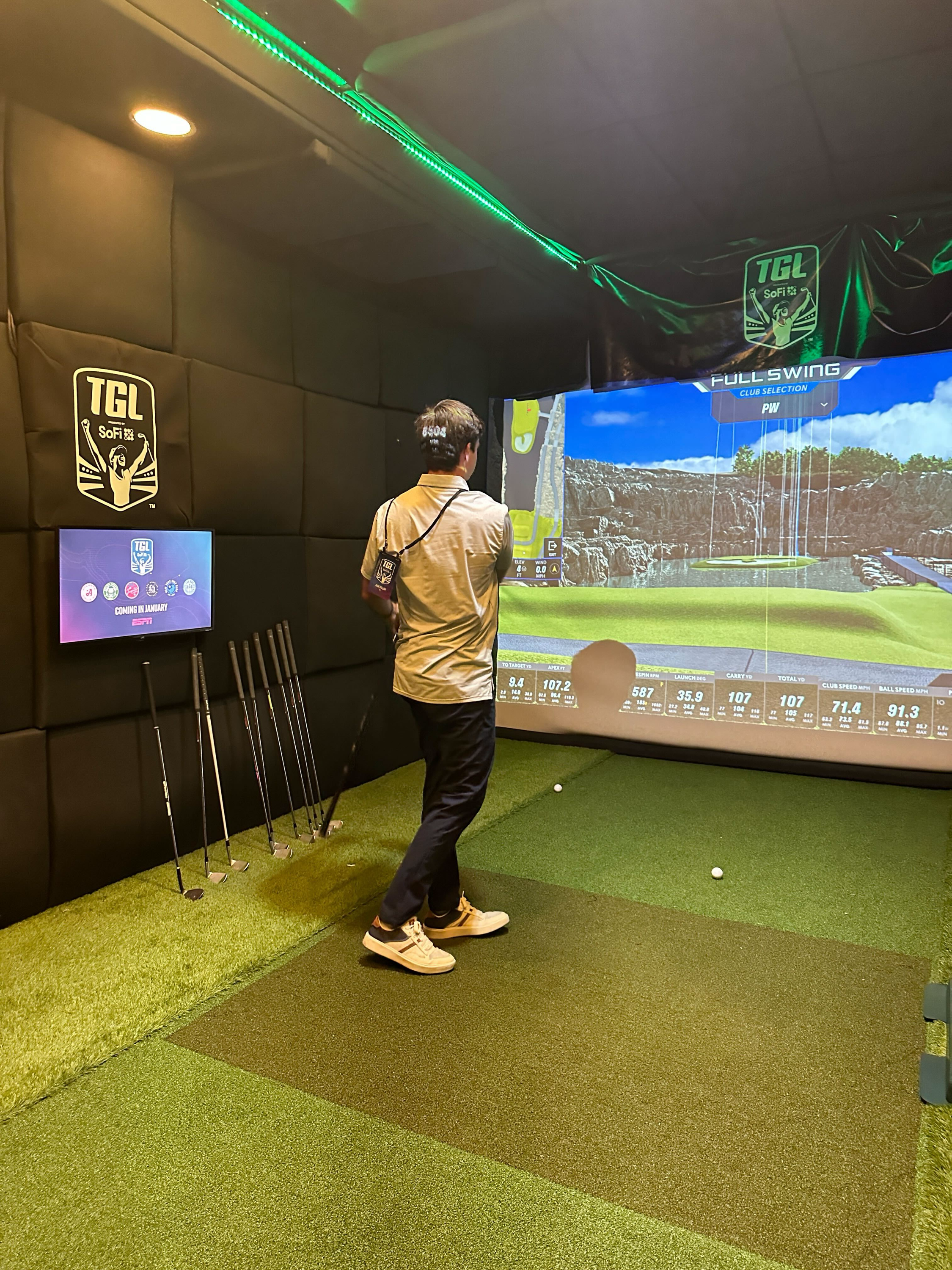 Inside a TGL × Dryvebox trailer — TGL SoFi branding on padded walls, Full Swing simulator software on screen, golfer mid-shot