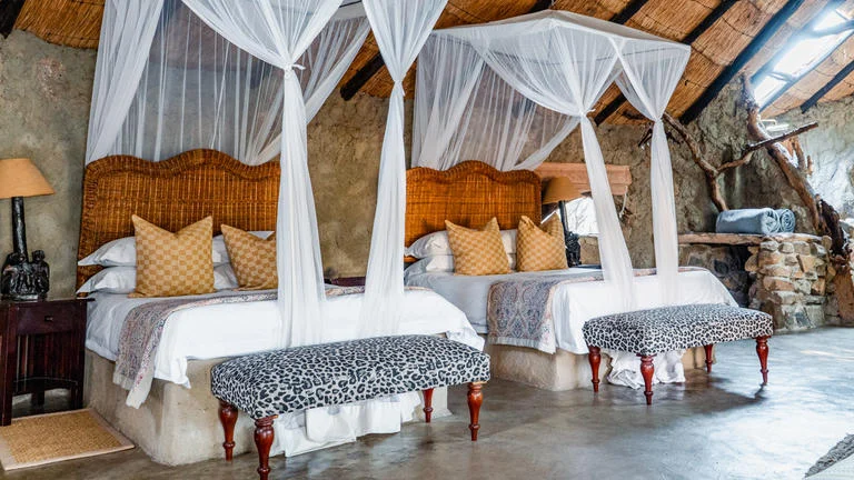 A spacious safari lodge family room with twin beds and mosquito nets