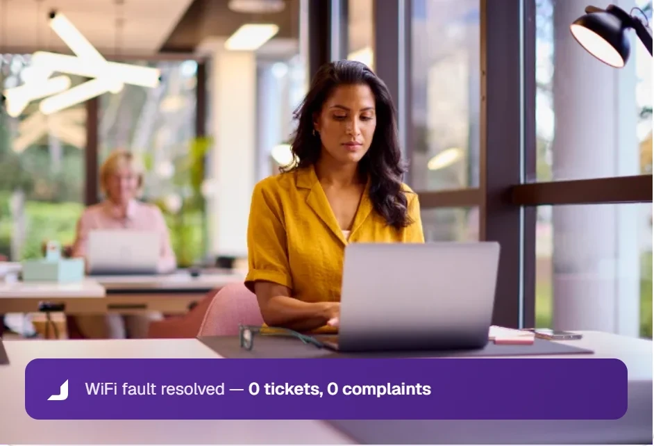 A workspace member working on a laptop after a WiFi fault was resolved with zero tickets or complaints.