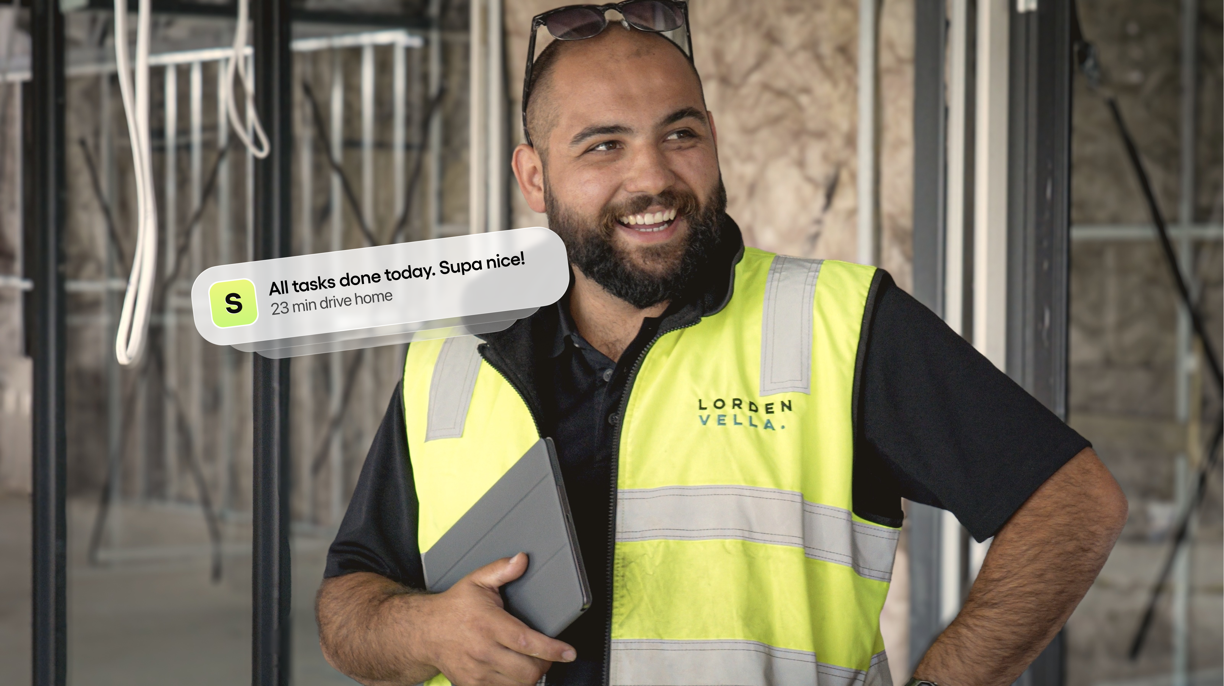 Smiling tradie holding a tablet on an active jobsite