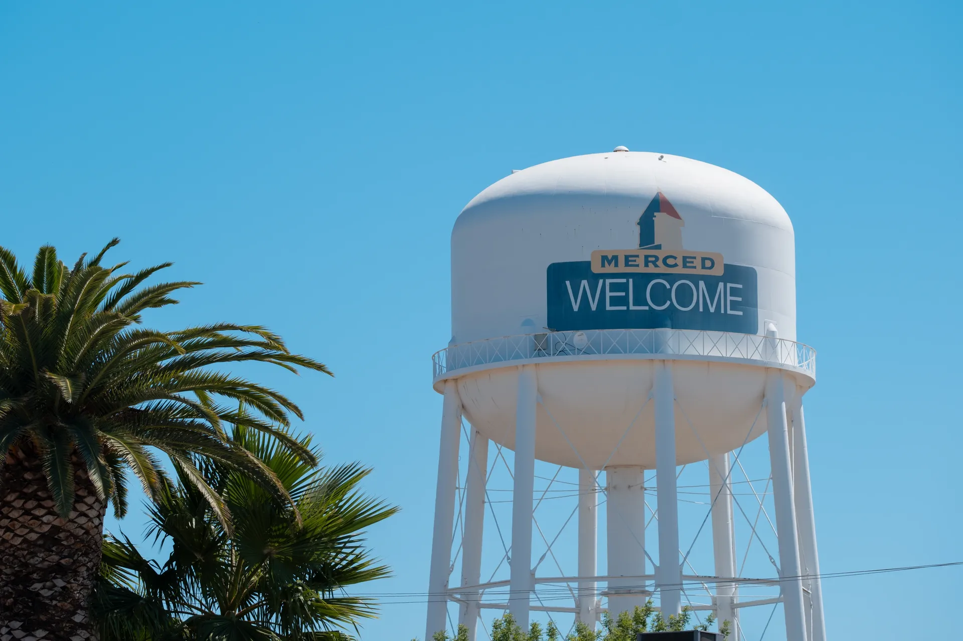 Merced water tower with a welcome sign against a blue sky in Merced, California