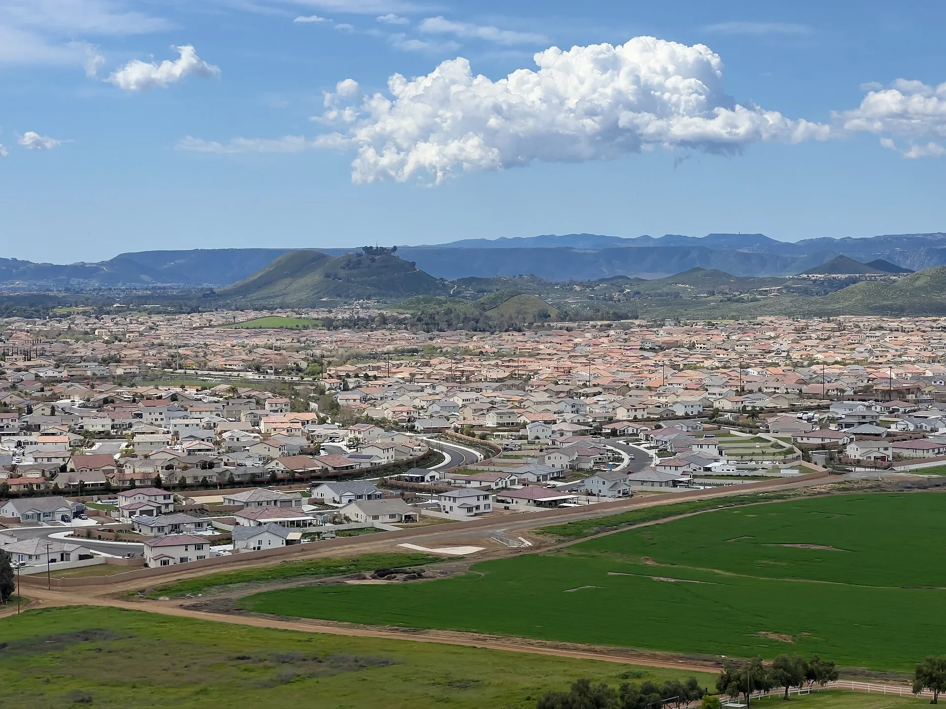Green field in French Valley with new neighborhoods and hills beyond, near Murrieta