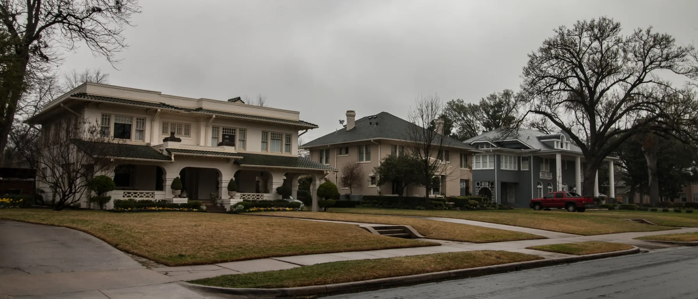 Large early 1900s two-story homes set back on wide lawns along Swiss Avenue in Dallas on an overcast day