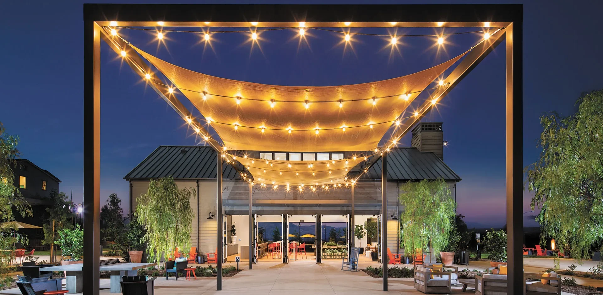 Hudson House clubhouse at Bedford in Corona, California, at dusk under strings of lights