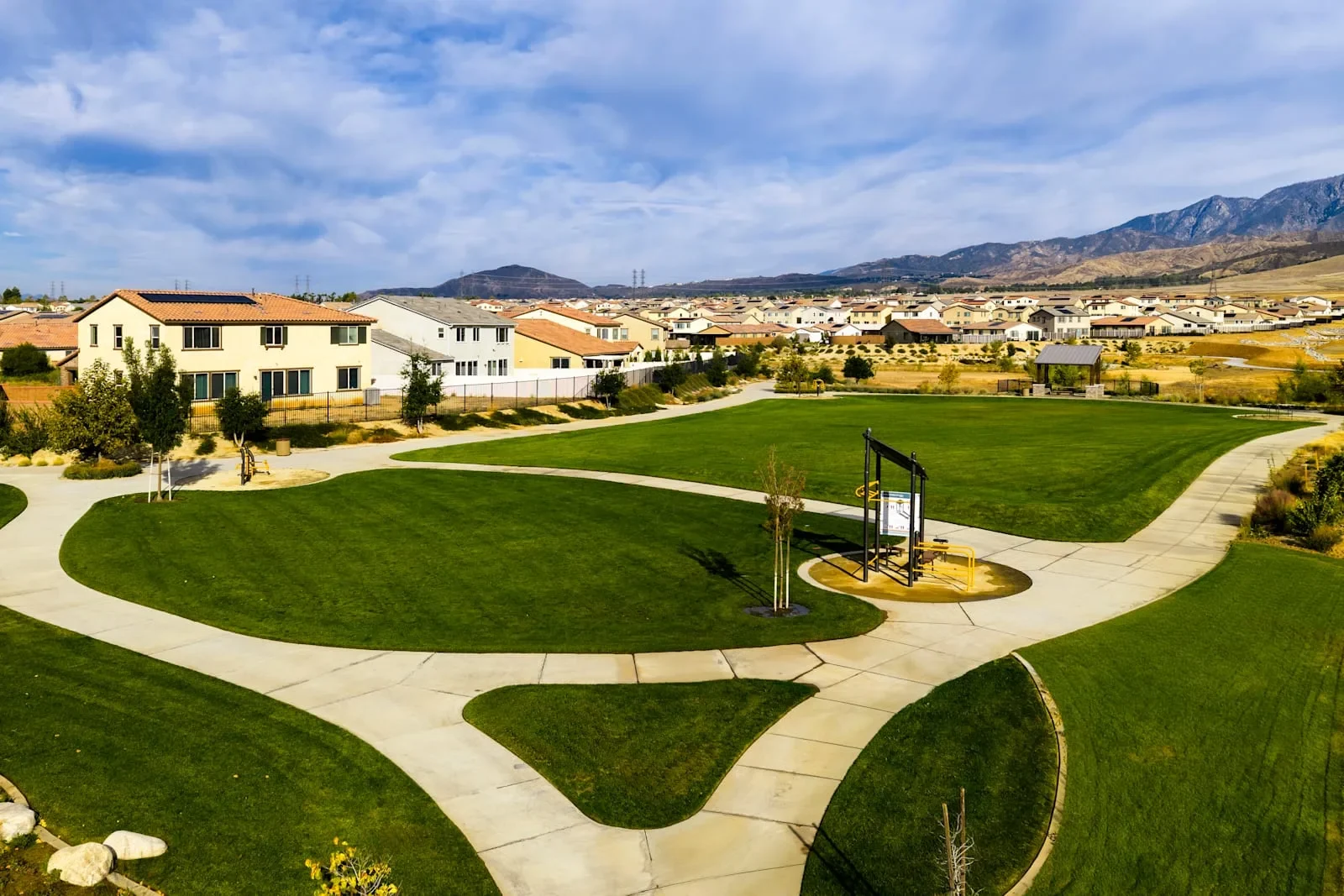 Park with curving lawns and walking paths in front of new homes at Atwell in Banning, California, with mountains behind