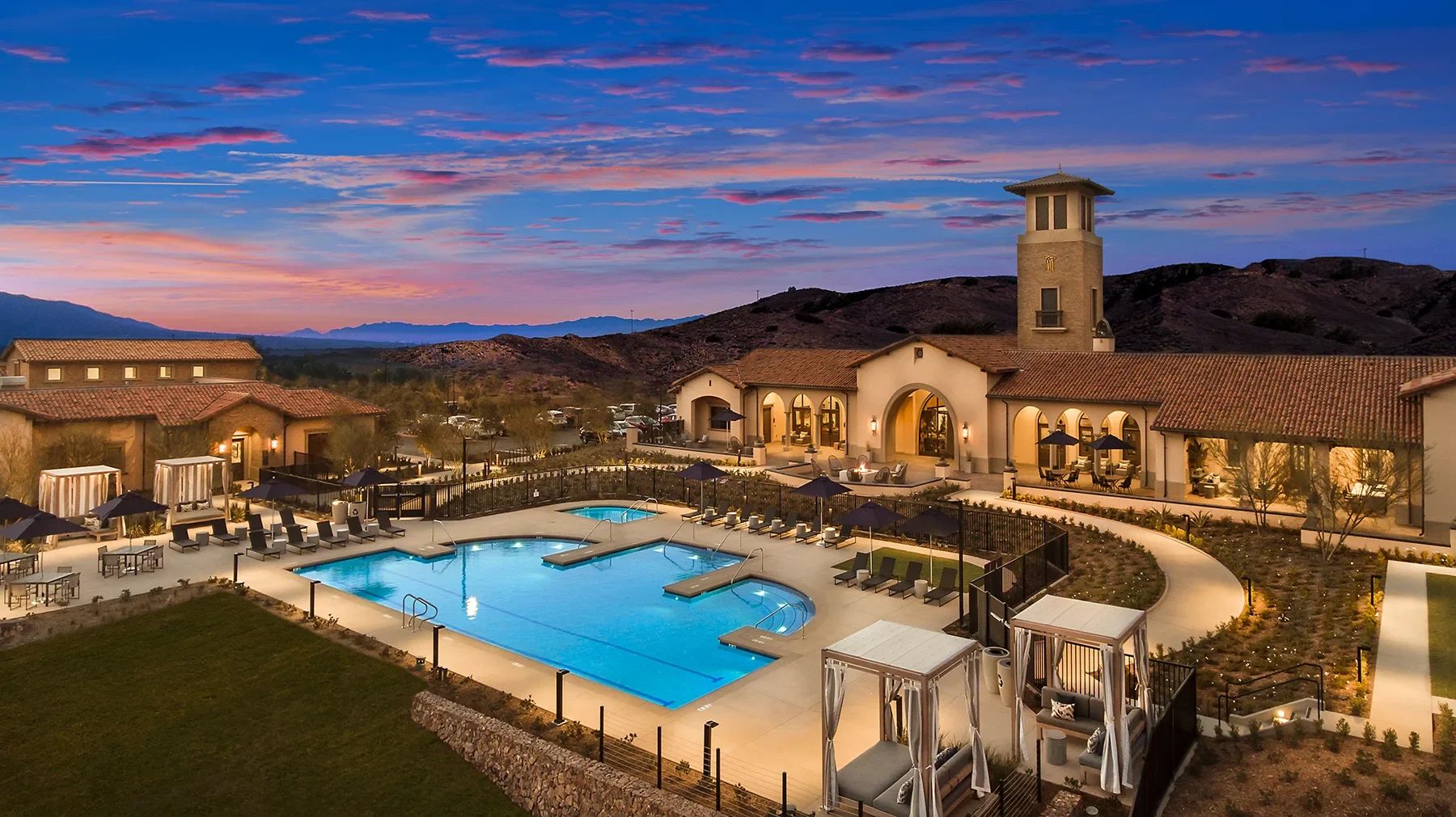 Resort pool and clubhouse with a bell tower at dusk at Terramor in Temescal Valley, California