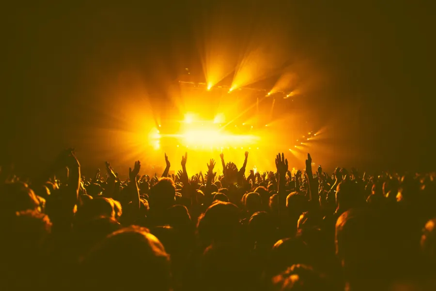 Concert audience beneath warm stage lighting during a live touring performance